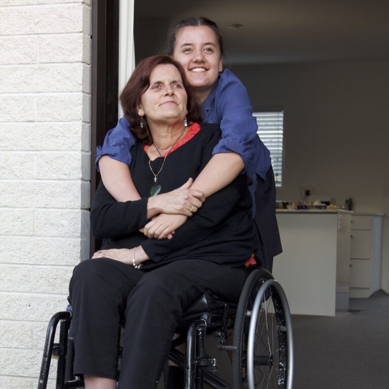 Judith in wheelchair with her supporter Amy giving her a hug