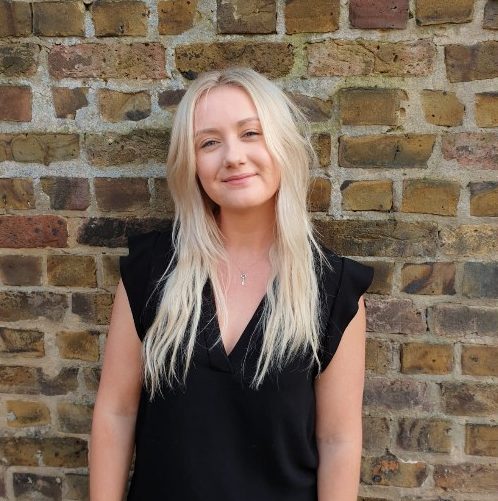 Head shot of Jessica Mills standing behind a brick wall