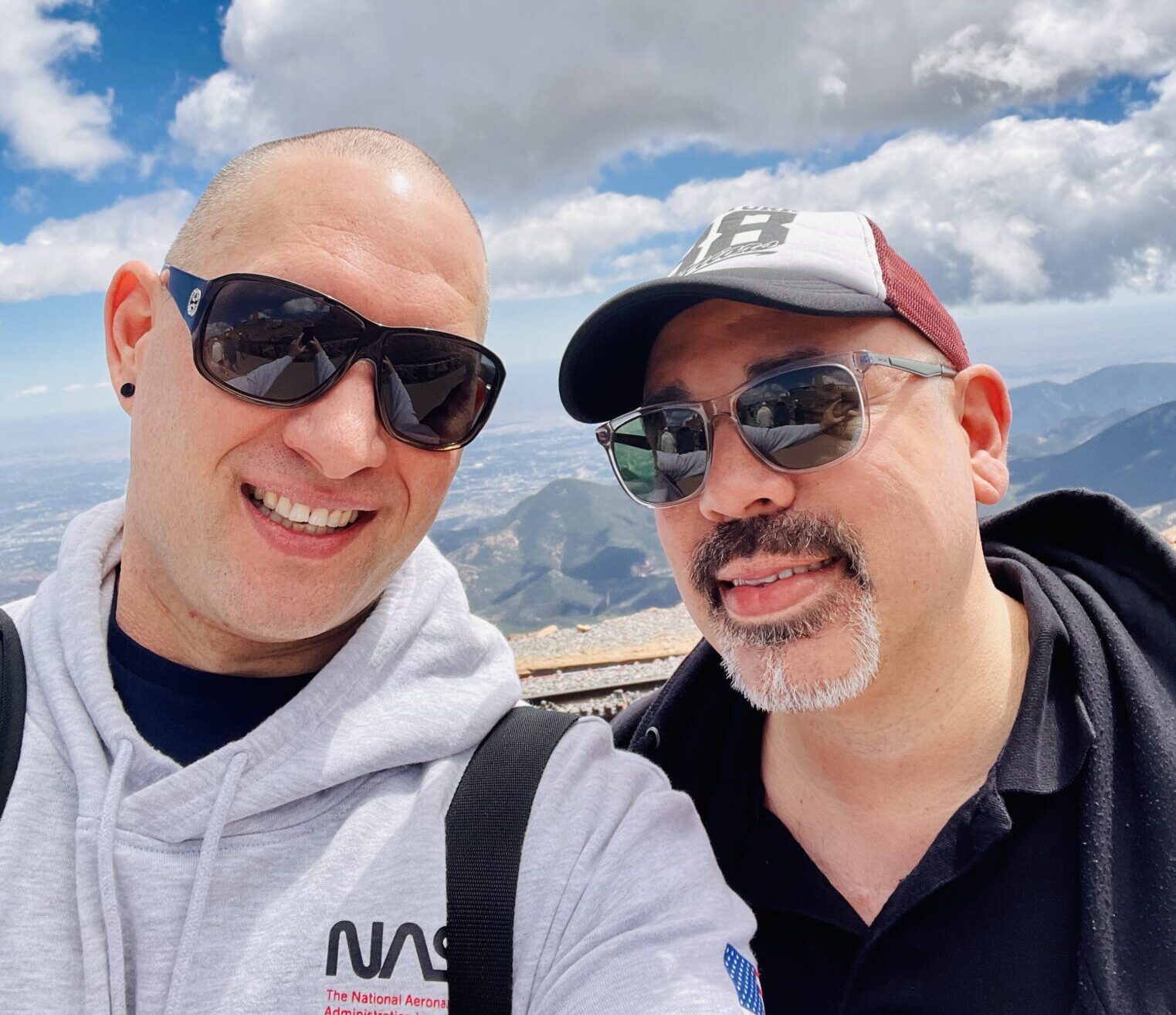 Geno smiling wearing sunglasses with husband michael 